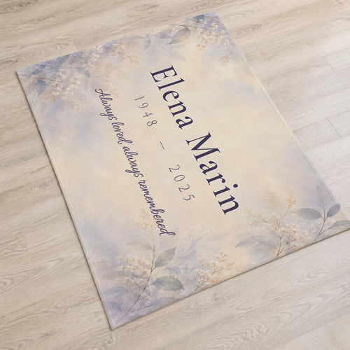 Always Remembered personalized memorial blanket with sample text "Elena Marin, 1948-2025, Always loved, always remembered", laid flat on the floor