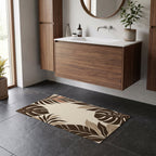 Kartela Monstera Frame washable tropical leaf bath mat in Beige, on a dark tile floor in front of a wooden vanity