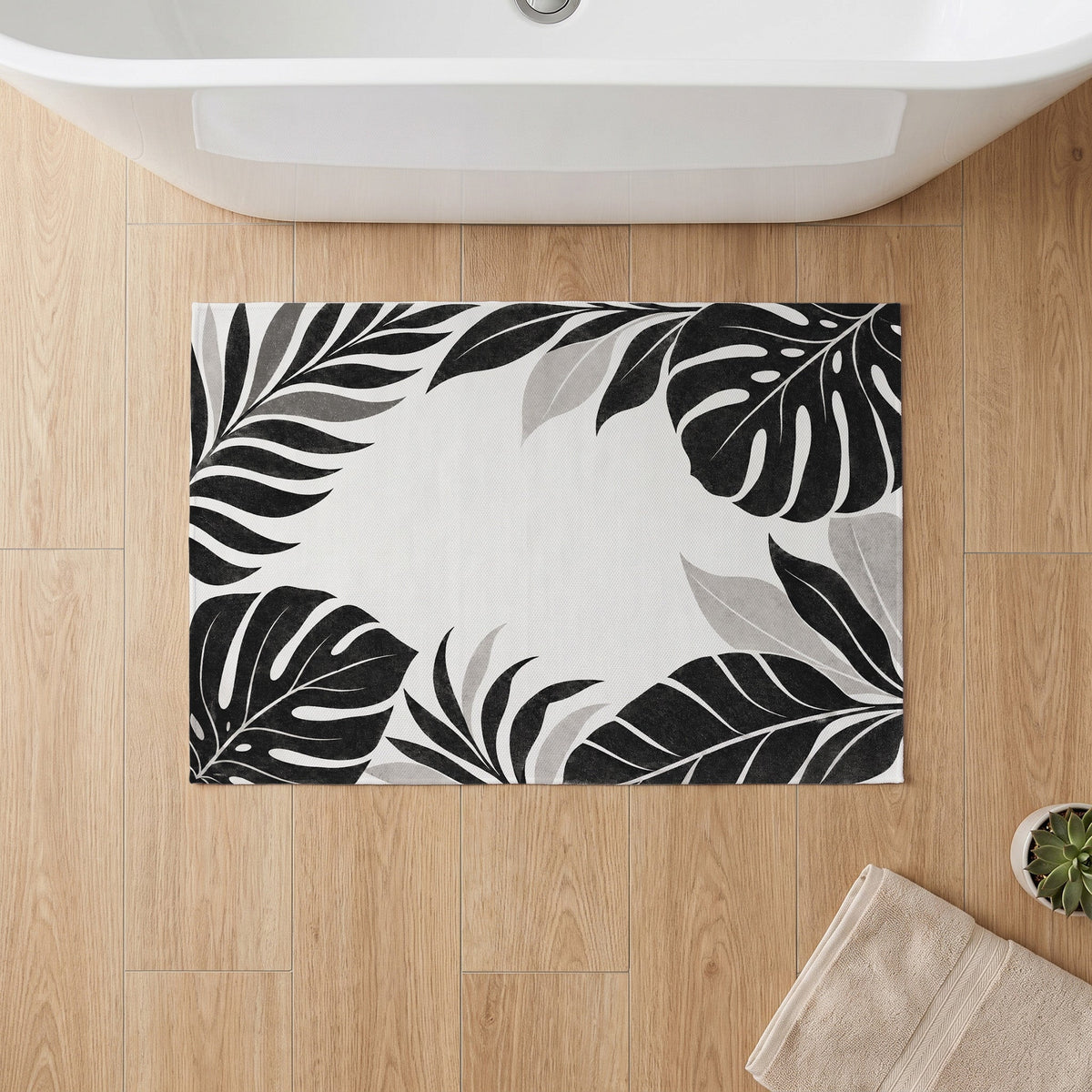 Kartela Monstera Frame washable tropical leaf bath mat in Black & White, on a wooden floor in front of a bathtub