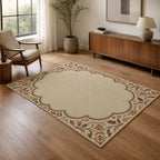 Kartela Cloud Frame washable classic bordered area rug in Beige, in a living room with an armchair and sideboard