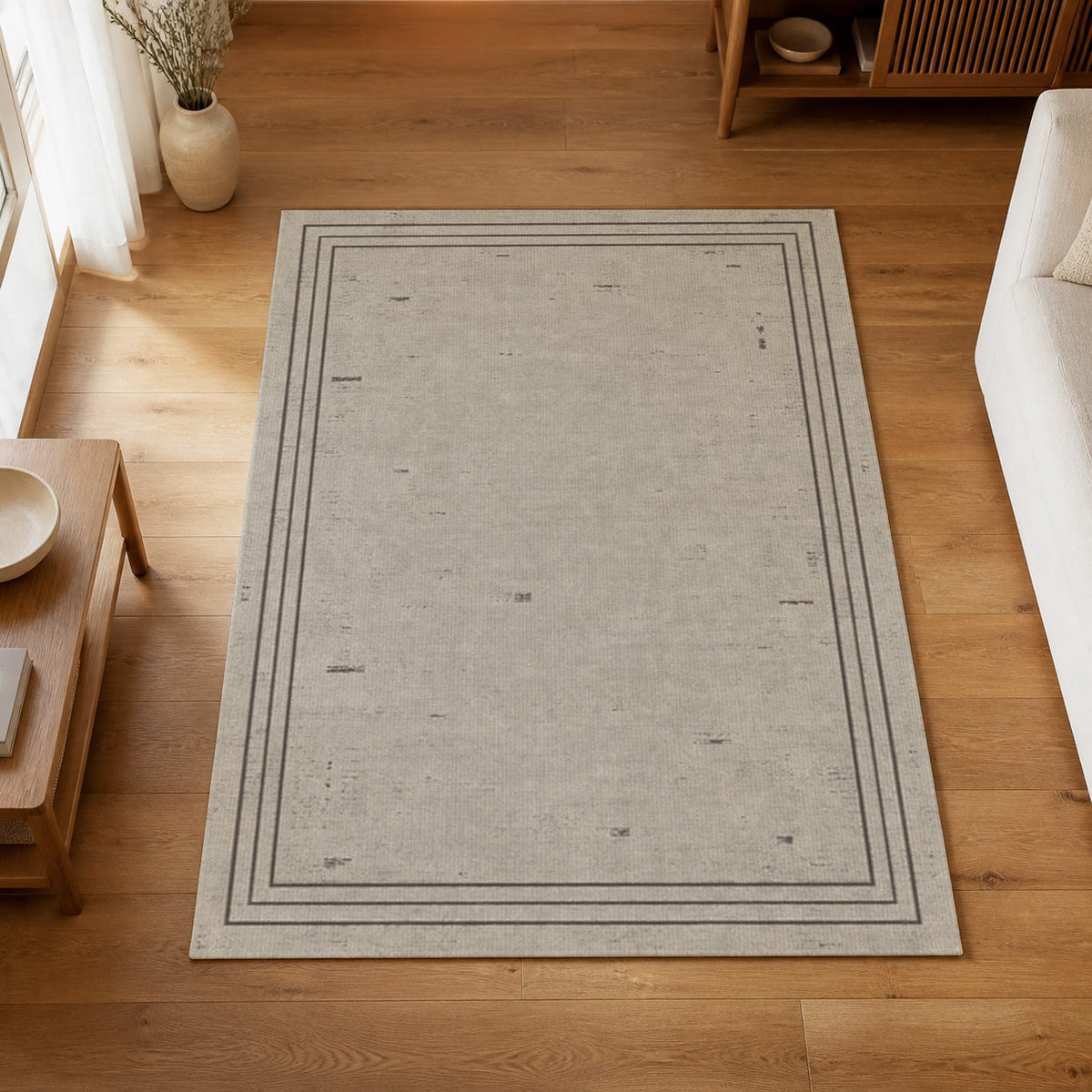 Kartela Weathered Line washable distressed bordered area rug in Light Gray, on a wooden floor in a bright living room