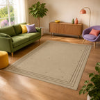 Kartela Weathered Line washable distressed bordered area rug in Beige, in a sunny living room with a green sofa