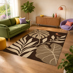 Kartela Night Garden washable tropical leaf area rug in Beige, in a sunny living room with a green sofa