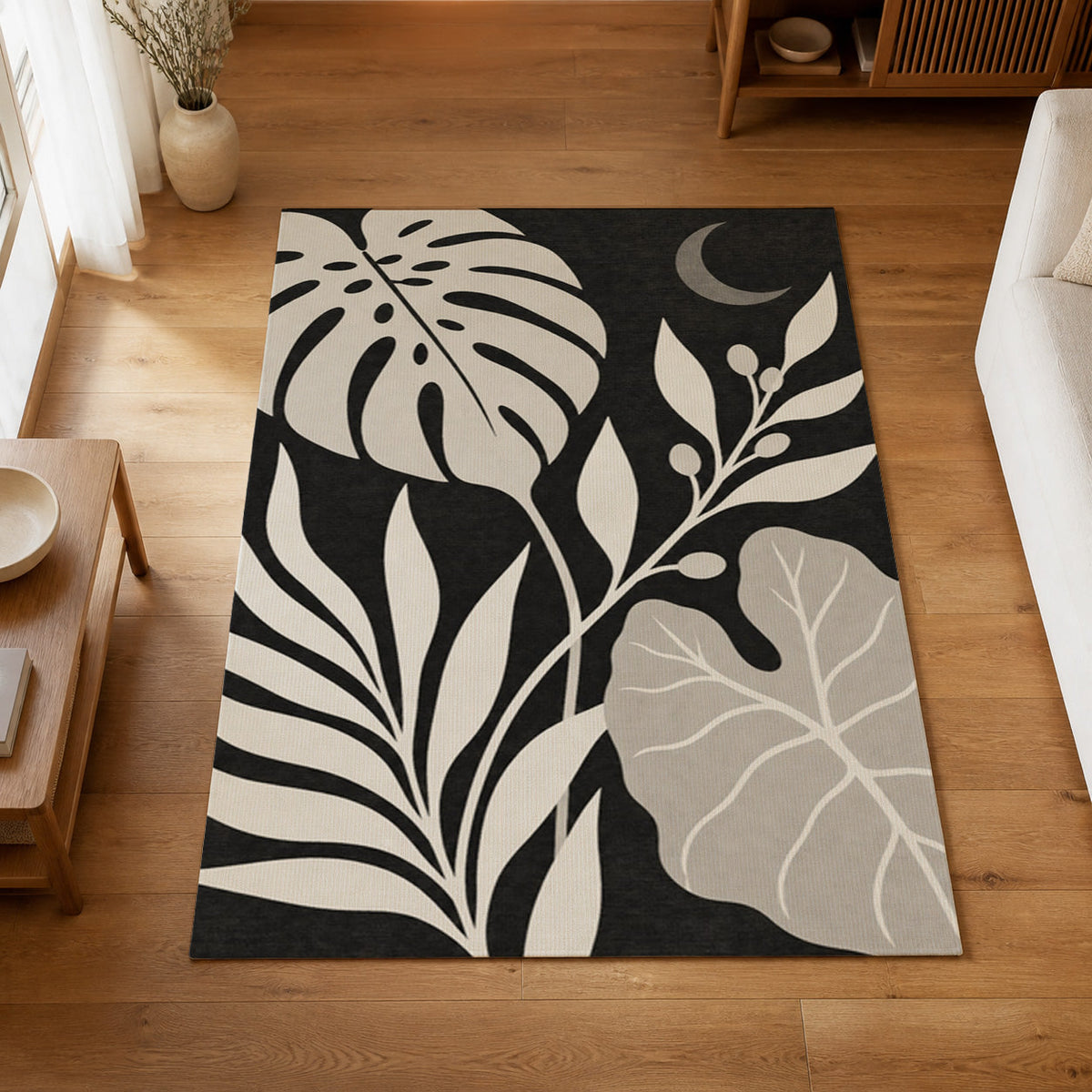Kartela Night Garden washable tropical leaf area rug in Black & White, on a wooden floor in a bright living room