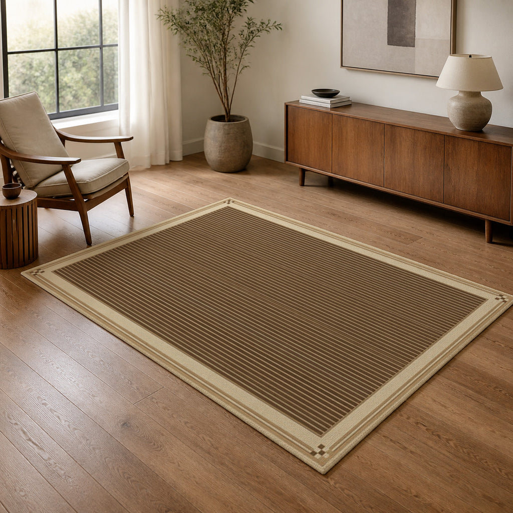 Kartela Fine Stripe washable striped bordered area rug in Beige, in a living room with an armchair and sideboard