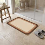 Kartela Jute Frame washable jute-look bath mat in Beige, in front of a glass shower with slippers