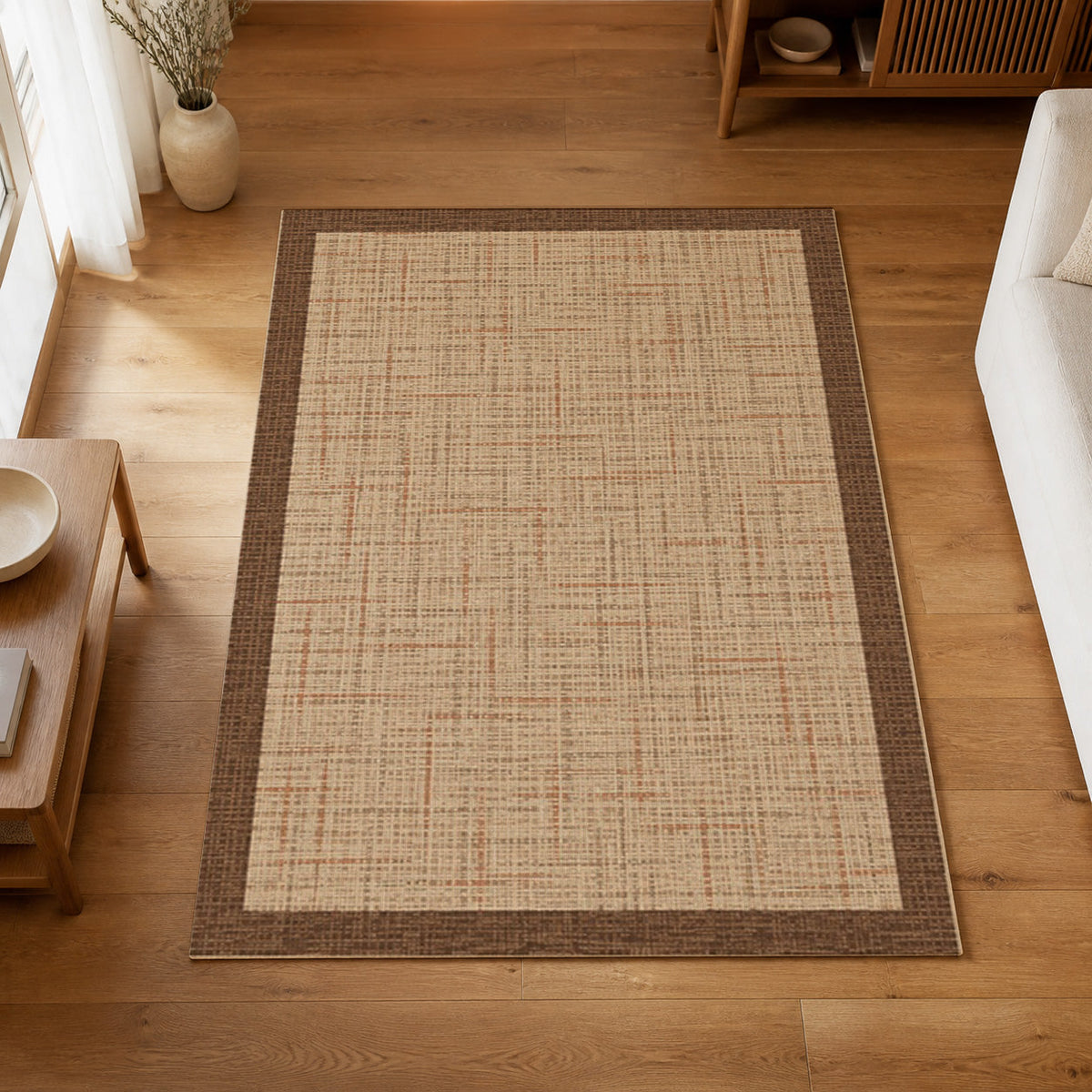 Kartela Jute Frame washable jute-look bordered area rug in Beige, on a wooden floor in a bright living room