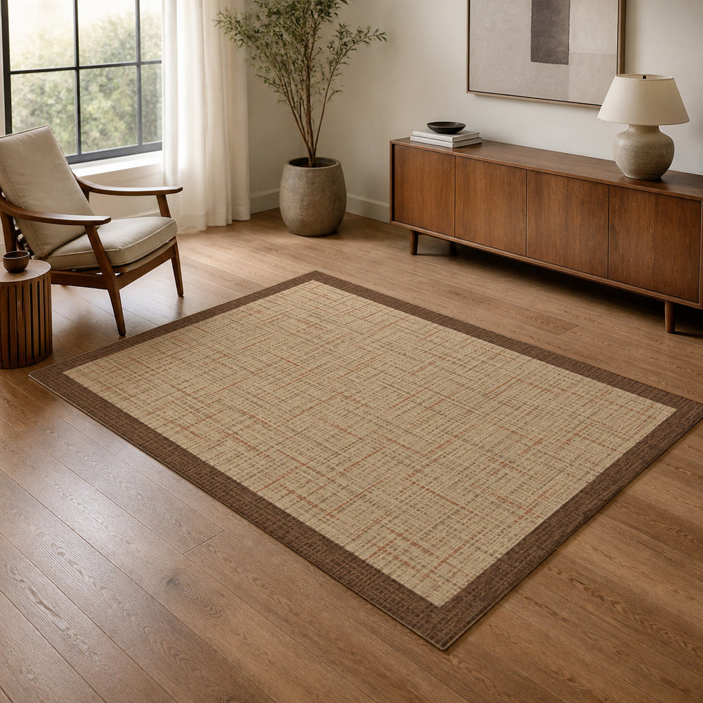 Kartela Jute Frame washable jute-look bordered area rug in Beige, in a living room with an armchair and sideboard